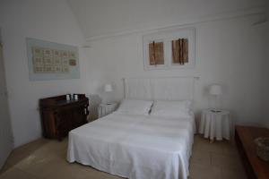 1 dormitorio con cama blanca y mesa de madera en Masseria Frassaniti by My Home Apulia, en Veglie