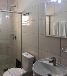 a bathroom with a toilet and a sink and a mirror at Cithos Hotel in Santa Cruz do Sul