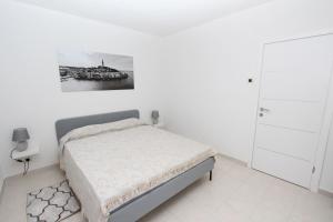 biała sypialnia z łóżkiem i zdjęciem na ścianie w obiekcie Apartment Stellina w Rovinj
