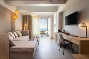 un soggiorno con divano e scrivania con TV di Portes Lithos Luxury Resort a Nea Potidaea