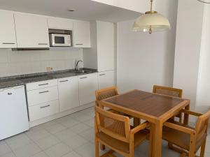 une cuisine avec des placards blancs et une table et des chaises en bois dans l'établissement Apartamentos Marina, à Port de Pollença