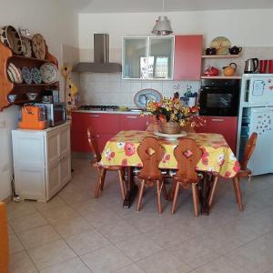 una cucina con tavolo e sedie e una cucina rossa di Casa vacanze Antonella Pula a 750mt dal centro. a Pula