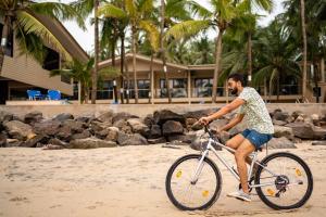 a man riding a bike on the beach at The Windmill Resorts in Malvan
