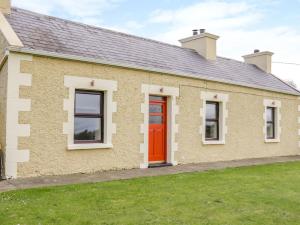 uma casa com uma porta vermelha e um quintal em Glor Cottage em Ballyhaunis