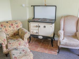 a living room with two chairs and a stove at Glor Cottage in Ballyhaunis