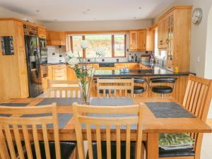 uma cozinha com armários de madeira e uma mesa de madeira com cadeiras em Rossanean em Farranfore