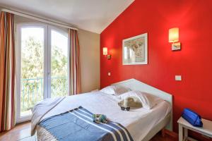a bedroom with a bed with a red wall at Résidence Pierre & Vacances le Hameau de la Pinède in Hyères