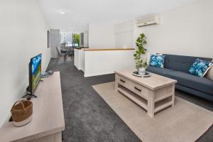 a living room with a blue couch and a table at 2-Bed Near Brisbane CBD with Pool, Sauna & BBQ in Brisbane