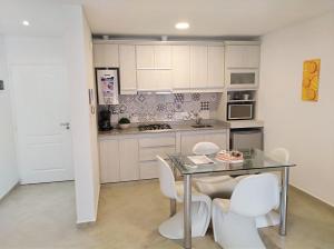a kitchen with a glass table and white chairs at Avalon in Concepción del Uruguay