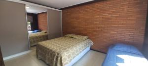 1 dormitorio con cama y pared de ladrillo en Roloff Praça das Rosas, en Gramado