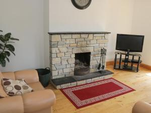 sala de estar con chimenea de piedra y TV en Kevin's House, en Achill