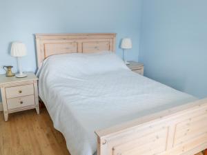a bedroom with a white bed and two night stands at Joe's Cottage in Ardara