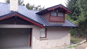 una casa con techo de metal y garaje en Departamento Victoria Bariloche en San Carlos de Bariloche