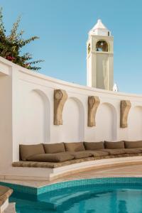 - un bâtiment blanc avec un canapé à côté de la piscine dans l'établissement Mitsis Petit Palais, à Rhodes