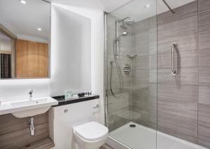 a bathroom with a shower and a toilet and a sink at Holiday Inn Belfast by IHG in Belfast