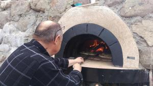 un hombre poniendo una pizza en un horno de piedra en Riverside Voerså en Sæby