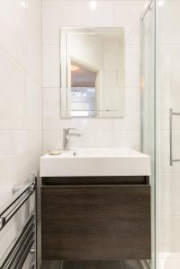 Baño blanco con lavabo y espejo en 12 Helena Luxury Serviced Apartment, en Reading