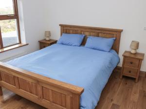 a bedroom with a bed with blue sheets and two tables at Kevin's House in Achill