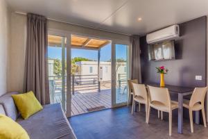 a living room with a dining room table and a balcony at Mobile homes Lussmarin in Mali Lošinj