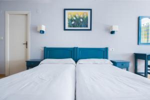 two beds in a bedroom with two blue tables at El Ciervo in Sierra Nevada