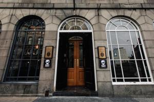 a building with three windows and a wooden door at BrewDog Kennels - Aberdeen in Aberdeen