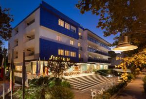 un grand bâtiment bleu avec une cour en face dans l'établissement Hotel Stacchini, à Cesenatico