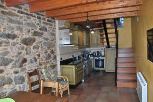 a kitchen with a stone wall and a table and chairs at Las Maticas in Molinaseca