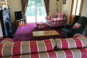 a living room with a couch and chairs and a tv at Sunny Bungalow in Courtown