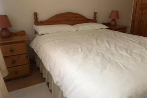 a bedroom with a large white bed and two night stands at Sunny Bungalow in Courtown
