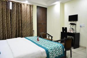 Dormitorio con cama, escritorio y TV en Hotel Kundan Palace, en Nueva Delhi