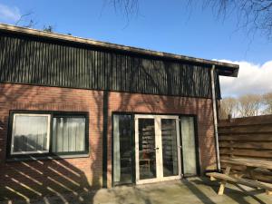 a brick building with a door and a bench at Polderhoek in Woubrugge