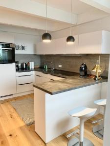 a kitchen with white cabinets and a counter with stools at Ferienwohnung Mountainlook in Hohegeiß