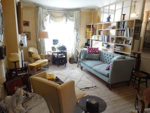 ein Wohnzimmer mit einem blauen Sofa und Stühlen in der Unterkunft Hurlingham Bed and Breakfast in London