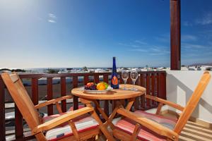 a table with two chairs and wine glasses on a balcony at Orquidea in Puerto Calero