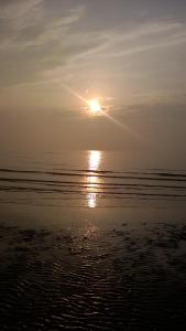 een zonsondergang boven het water op het strand bij Chez Marie in Duinkerke