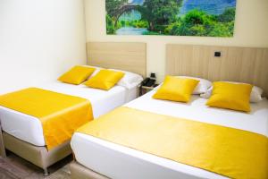 two beds in a room with yellow pillows at Hotel Street 50 Estadio in Medellín