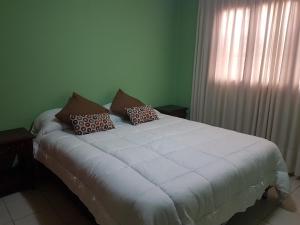 una cama blanca con almohadas en una habitación en Casa Cerro de la Luna en Salta