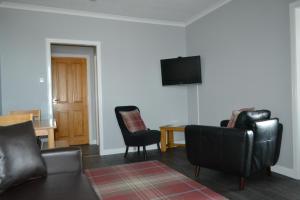 a living room with two leather chairs and a television at Harbour View Apartment Wick in Wick