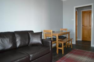 een woonkamer met een leren bank en een tafel bij Harbour View Apartment Wick in Wick