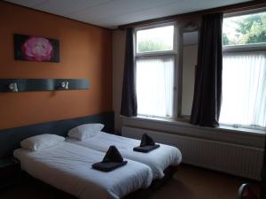 a bedroom with two beds with black pillows on them at Zorn Hotel Duinlust in Noordwijk aan Zee
