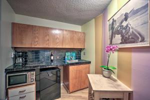a kitchen with wooden cabinets and a table with a vase of flowers at Downtown Honolulu Suite Near Ala Moana Beach! in Honolulu