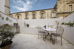 a patio with a table and chairs on a balcony at Nicotera Apartment in Noto