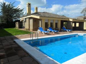 una casa con piscina frente a una casa en Villas Aloha Valdelagrana, en El Puerto de Santa María