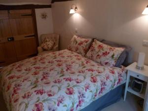 a bedroom with a bed with a floral bedspread and a chair at Kings Cottage in Wokingham