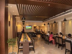 a group of people sitting at tables in a restaurant at Hotel Ballerina in Tinsukia