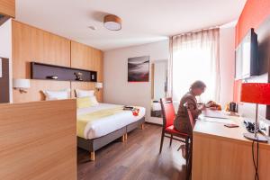 a woman sitting at a desk in a hotel room at Apparthotel Privilodges Carré de Jaude in Clermont-Ferrand