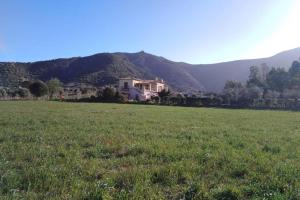 una casa en un campo con montañas en el fondo en Agriturismo Donnolù, en Tertenìa