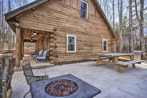 a log cabin with a picnic table and a fireplace at Stylish Creekside Cabin with Fire Pit Near Wineries! in Pittsville