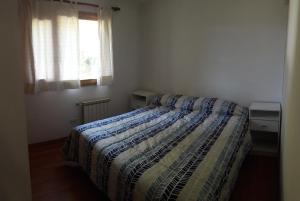 ein Schlafzimmer mit einem Bett mit einer Bettdecke und einem Fenster in der Unterkunft Departamento Victoria Bariloche in San Carlos de Bariloche
