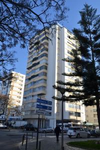 un edificio blanco alto con letreros de la calle delante de él en Torres Mira Praia by Garvetur, en Quarteira